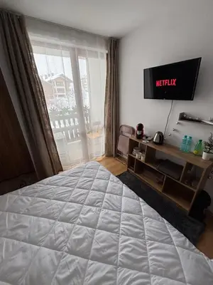a bedroom with a large bed and a television at Smart Stay - Refurbished Studio with Balcony and Parking in Bansko