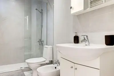 a white bathroom with a toilet and a sink at Prime Central Sofia Living Modern 2BR Apt in Sofia