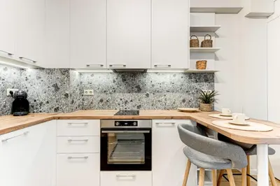 a kitchen with white cabinets and a wooden table at Prime Central Sofia Living Modern 2BR Apt in Sofia