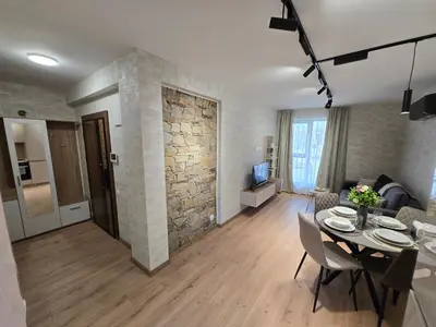 a living room with a dining table and a living room with a stone wall at Plovdiv Hills Apartments with FREE Parking in Plovdiv