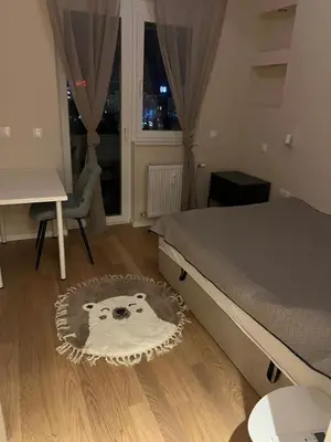 a bedroom with a bed and a table and a window at Lux, Spacious and Comfort Apartment next to National Palace of Culture in Sofia