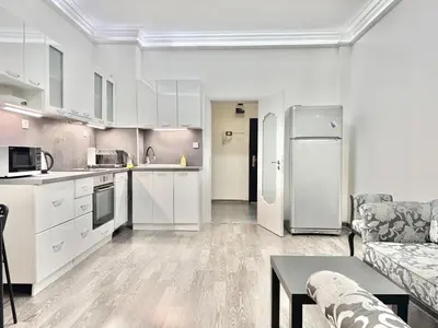 a kitchen and a living room with white cabinets at Top City Centre 1BDR Apartment next to Theater Tear and Laughter in Sofia
