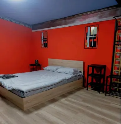 a bedroom with a bed with an orange wall at MOTEL Route 80 in Bozhurishte