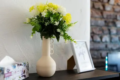 a white vase with yellow and white flowers on a table at 1 min from NDK and Vitoshka street in Sofia