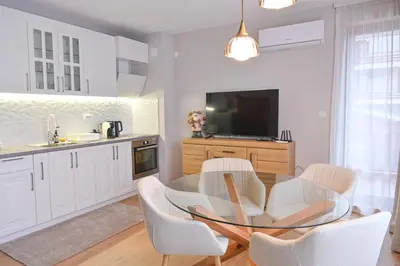 a kitchen with a glass table and white chairs at 2 Luxurious one bedroom apartments 5 minute walk from the Gondola station in Bansko