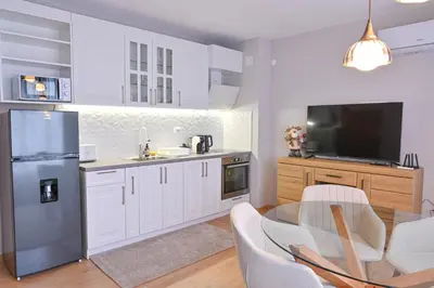 a kitchen with white cabinets and a stainless steel refrigerator at 2 Luxurious one bedroom apartments 5 minute walk from the Gondola station in Bansko