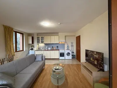 a living room with a couch and a tv in it at Bansko Bliss - Peaceful Stay with Balcony Views in Bansko