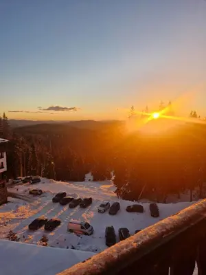 a view of a snow covered parking lot with the sun setting at WoodLux in Pamporovo