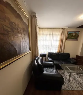a living room with two leather couches and a window at Кольовата къща Тетевен in Teteven