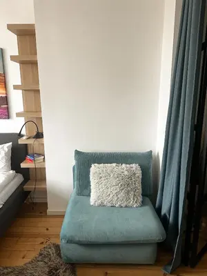 a blue chair with a pillow on it in a room at Serdika Central Stay - 2BD next to Serdika Metro Station in Sofia