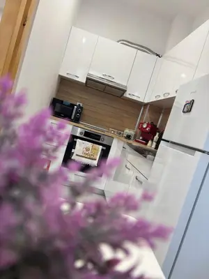 a kitchen with white cabinets and purple flowers in the foreground at Luxury & Comfort near the University in Blagoevgrad