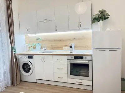 a kitchen with white cabinets and a washer and dryer at Center Chill ARTpartment in Sofia