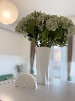 a white vase with flowers on a table at Center Chill ARTpartment in Sofia