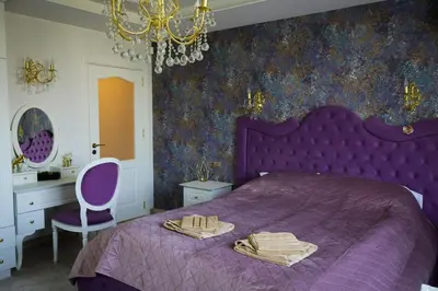 a bedroom with a purple bed and a chandelier at Апартамент за гости Марица in Asenovgrad