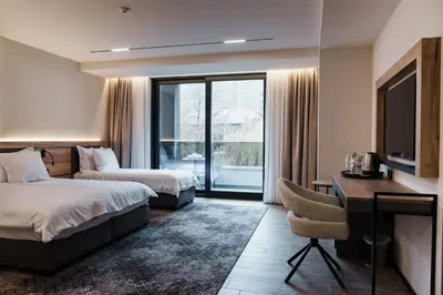 a hotel room with two beds and a desk at Семеен хотел РАЙ in Ognyanovo