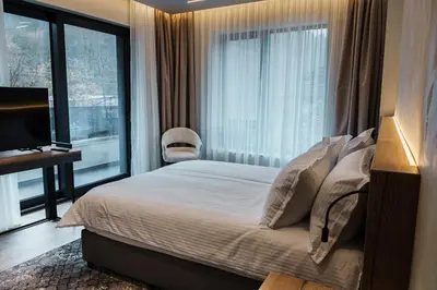 a bedroom with a bed and a large window at Семеен хотел РАЙ in Ognyanovo