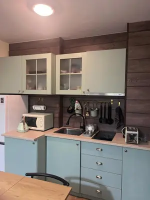 a kitchen with white cabinets and a microwave at Apartment at the foot of Pirin in Bansko