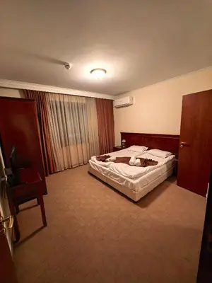 a hotel room with a large bed and a chair at Mountain Heaven Downtown in Bansko