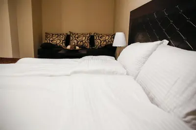a bedroom with two white beds and a black headboard at Einstein House & Spa in Marchevo
