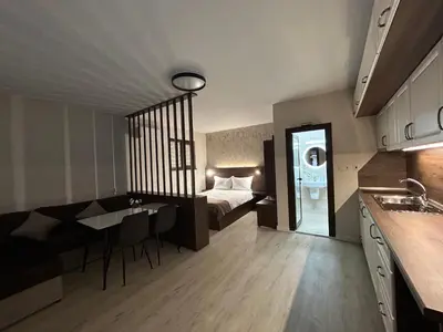 a room with a bed and a table and a kitchen at Алтъна Калофер in Kalofer