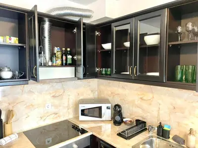 a kitchen with black cabinets and a microwave on a counter at The Mountain Hug 1BR by SI Stay in Bansko