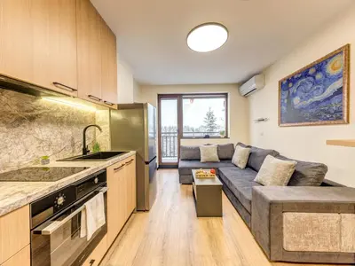 a large living room with a couch and a kitchen at Alpine Glow Studio with Parking Pamporovo in Pamporovo