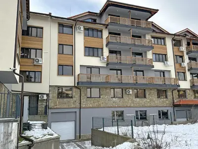 an apartment building with a garage in the snow at New! Park Lane Bansko Residences in Bansko