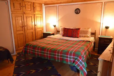 a bedroom with a bed with a plaid blanket at Guest House Zlatniyat Telets in Koprivshtitsa