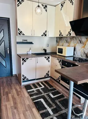 a kitchen with white and black cabinets and a microwave at Cozy apartment kids friendly in Sofia