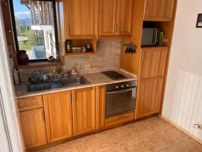 a kitchen with wooden cabinets and a sink and a window at Villa Dreams in Golf Club Ibar in Dolna Banya