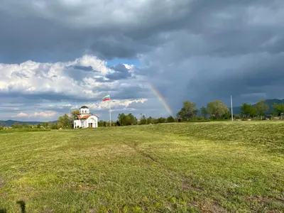 a rainbow in a field with a house and a kite at Villa Dreams in Golf Club Ibar in Dolna Banya