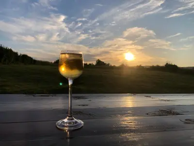a glass of wine sitting on a table with the sunset at Villa Dreams in Golf Club Ibar in Dolna Banya