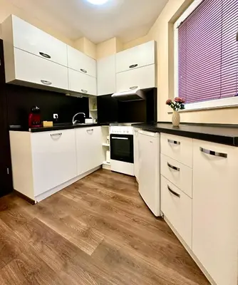 a kitchen with white cabinets and a black counter top at Ikigai Living - Cozy Studio in Studentski Grad in Sofia