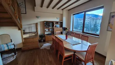 a dining room with a table and chairs and a window at 3 bedroom Penthouse only 700 meters from Ski Lift in Bansko