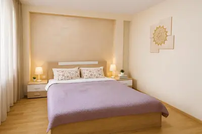 a bedroom with a bed with two nightstands and two lamps at Prime Apartment Seven & Parking in Plovdiv