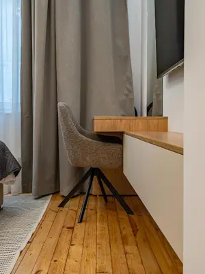 a desk with a chair next to a curtain at Stylish New High-End 3BR Apt on Vitoshka Blvd in Sofia