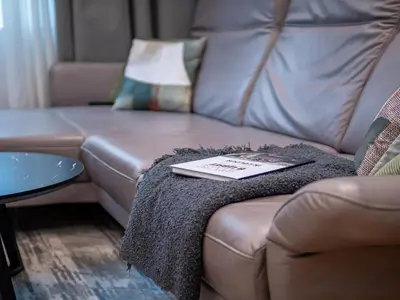 a brown leather couch with a book on a blanket at Stylish New High-End 3BR Apt on Vitoshka Blvd in Sofia
