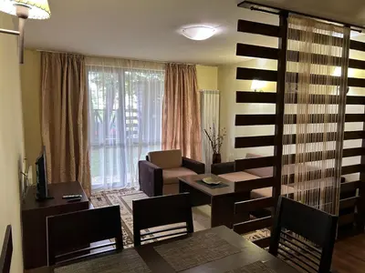 a living room with a dining table and a living room with a couch at Частен апартамент Банско in Bansko