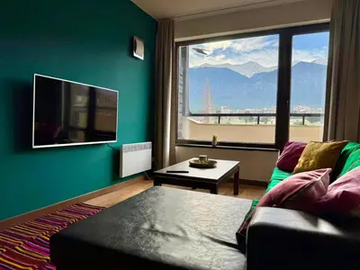 a living room with a couch and a large window at Golf view in Razlog