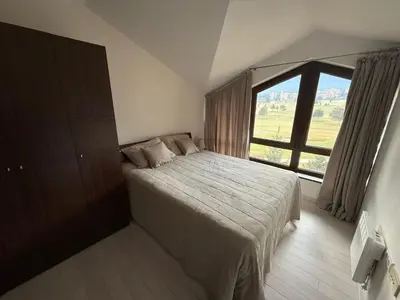 a bedroom with a bed and a large window at Golf view in Razlog