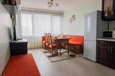 a kitchen with a table with chairs and a refrigerator at Апартамент в центъра на Хисаря in Hisarya
