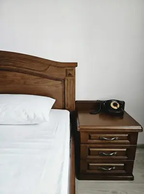 a bedroom with a bed and a nightstand with a phone on it at Апартамент в центъра на Хисаря in Hisarya