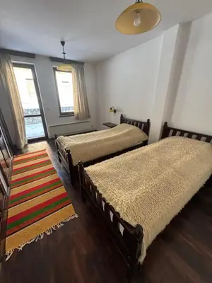 a bedroom with two beds and a rug at Къща за гости Пампорово в махала Кочорите in Pamporovo