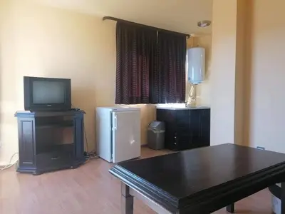 a living room with a table and a television at Свети Георги in Tsigov Chark