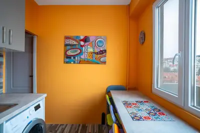 a kitchen with an orange wall with a table and a window at Life in Colours - Artistic 1BD Apartment in Sofia