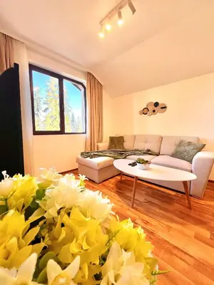 a living room with a couch and a table and flowers at Pamporovo Cozy Ski-Close Nest in Pamporovo