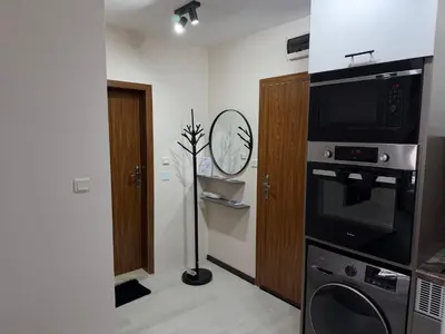 a room with a microwave oven and a clock on the wall at Elizi2 winter apartments Pamporovo in Pamporovo