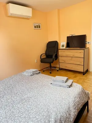 a bedroom with a bed and a chair and a television at New cozy apartment with undefloor heating 86m2 in Sofia