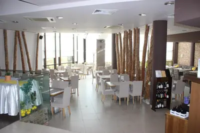 a restaurant with white chairs and tables and windows at Comfort apartment in the house in Razlog