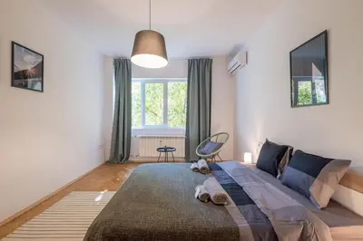 a bedroom with a large bed and a chair at Beautiful Bright and Spacious Central Apt in Sofia